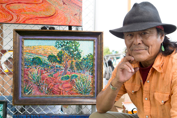 Shonto Begay, a Navajo painter, with one of his works at the Indigenous Fine Art Market. Gabriella Marks for The New York Times.