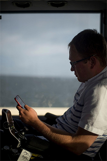 Mr. Morris checks his phone on the trip to Tampa, Fla. An accessibility consultant, he writes a blog on wheelchair travel. Zack Wittman for The New York Times.